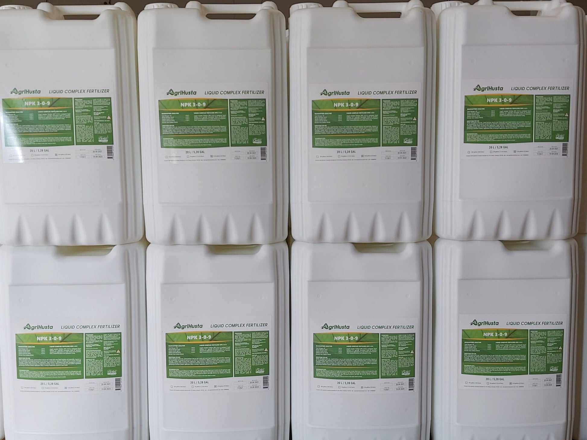 Multiple containers of AgriHusta liquid complex fertilizers with green labels.